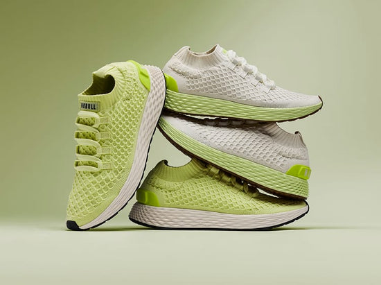 promo - Allday Knit Shoes in a stacked studio arrangement on a soft green background. The shoes feature a textured knit upper in light lime green and white, with a thick white midsole and small neon green accents.